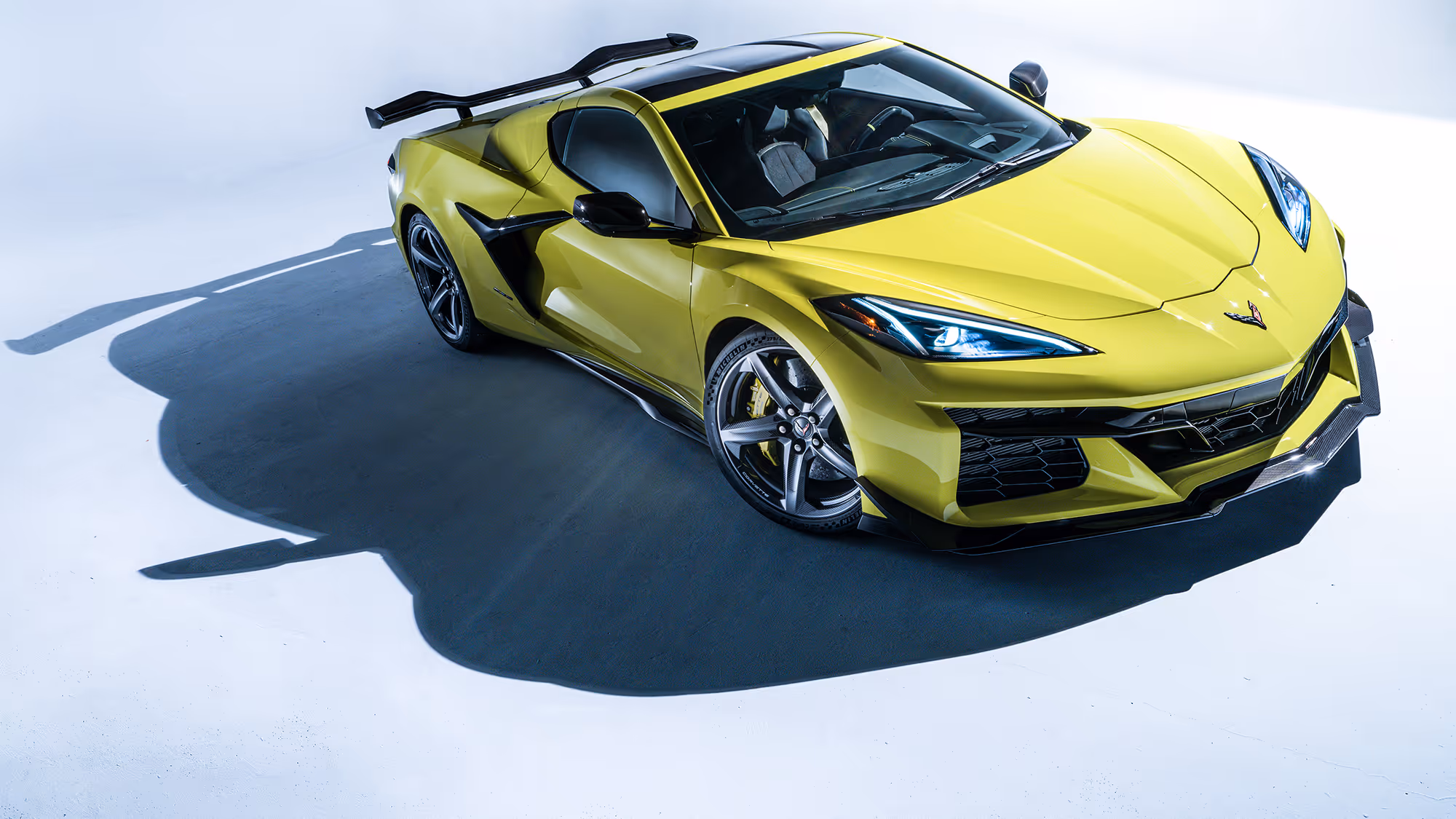 Front three-quarter view of Corvette Z06 with aggressive stance, sharp headlights, and defined body lines under high-contrast lighting.