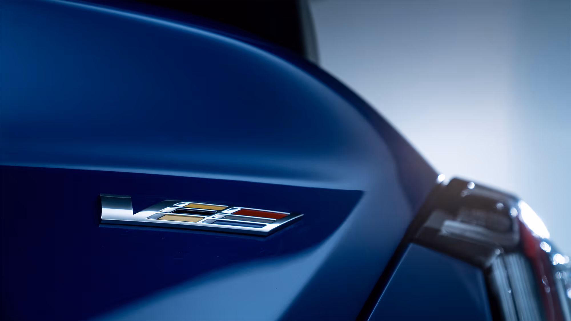 Blue Cadillac Blackwing rear badge detail with soft studio lighting and smooth reflections.