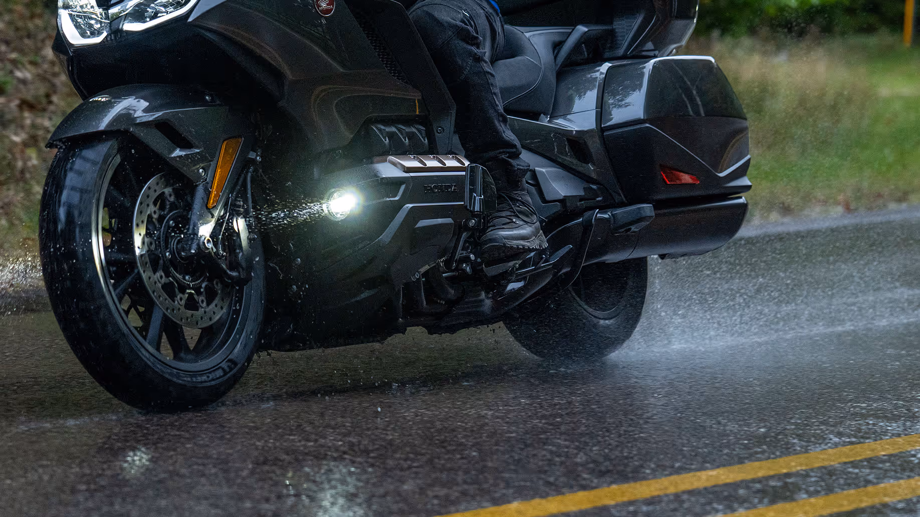 Low-angle close-up of Gold Wing front wheel and fairing on wet pavement