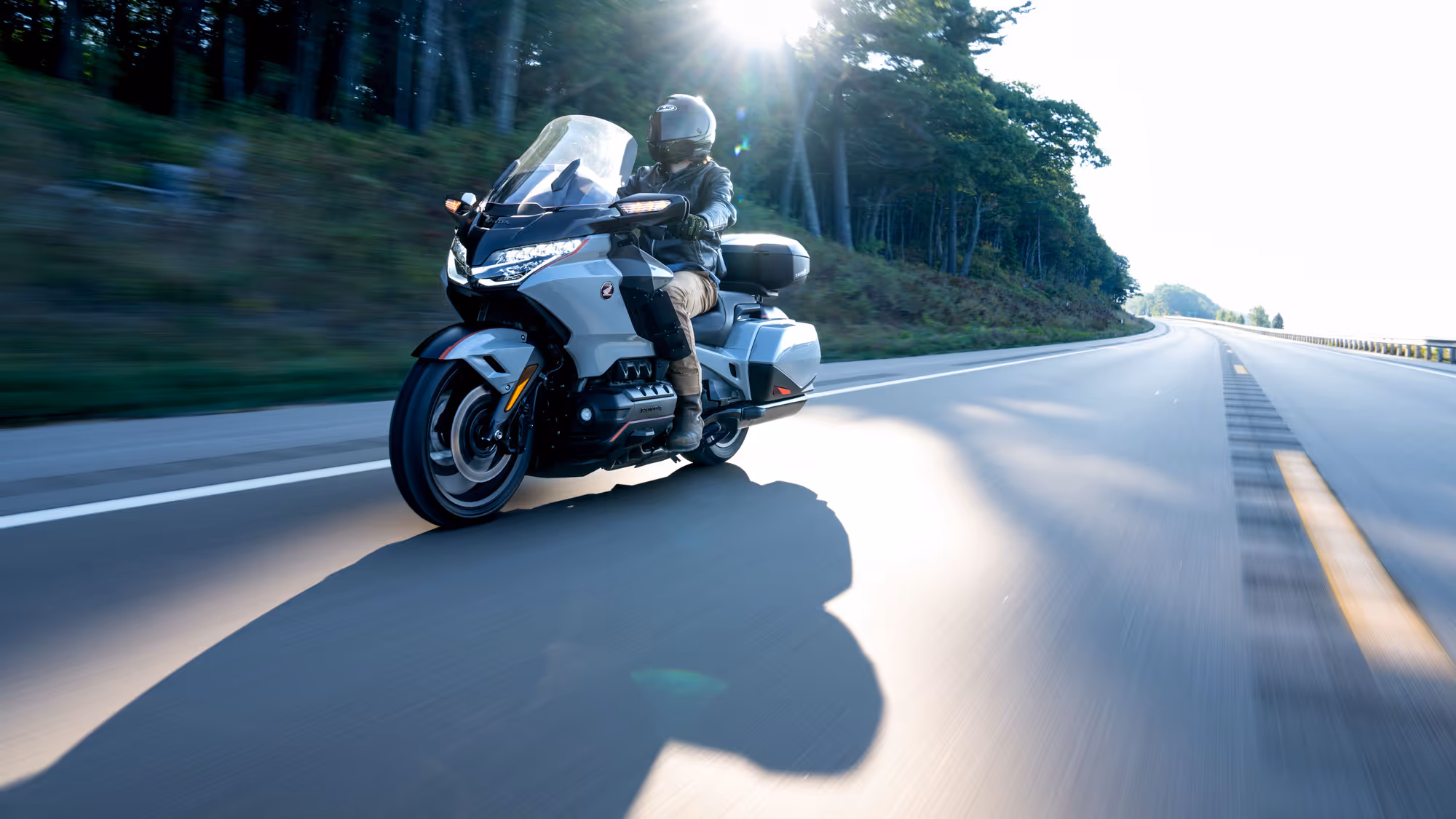 Silver Gold Wing approaching head-on with sun flare on an open highway