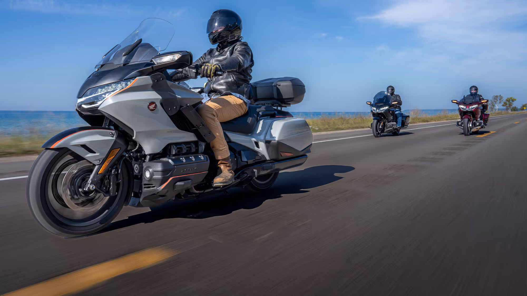 Group of three Gold Wings riding through a tree-lined curve with motion blur