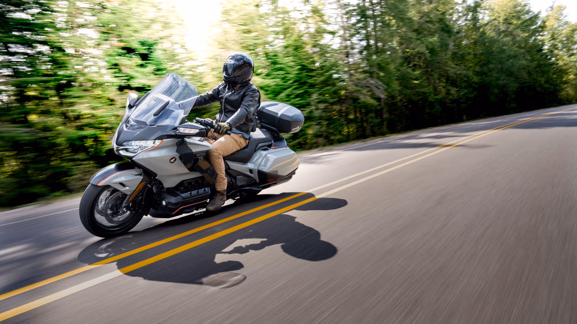 Silver Gold Wing leaning into a curve on a two-lane road through autumn foliage