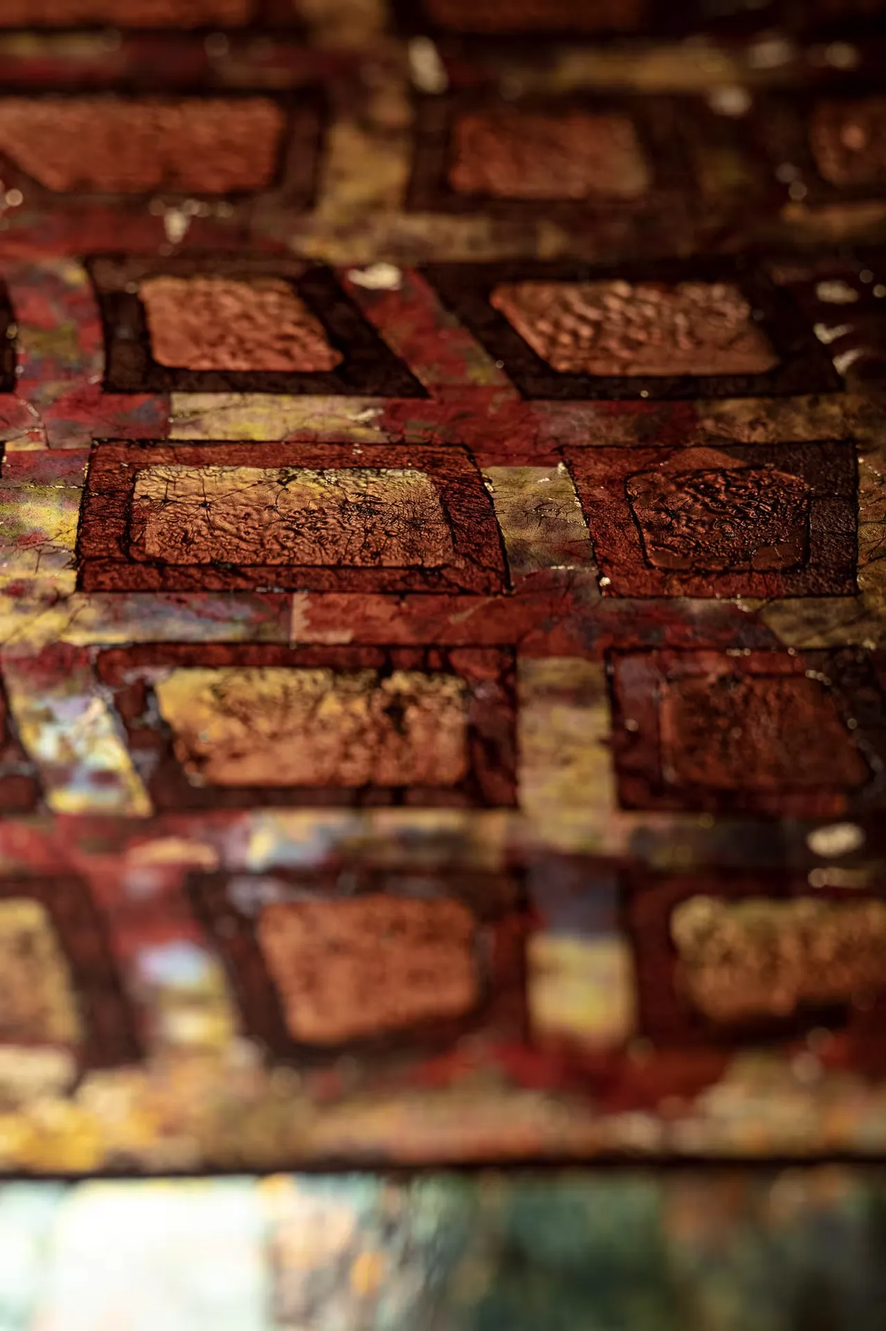 Close-up of textured, rectangular patterns in earthy tones on a surface with cracks and an aged look.