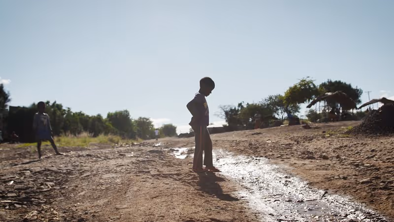 A young boy standing on a dirt road