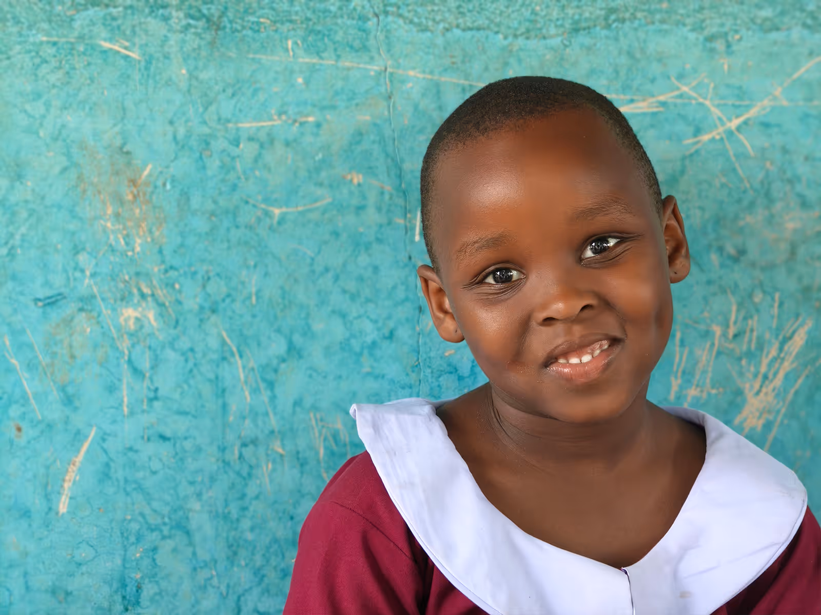 Smiling young girl with braided hair wearing a white striped shirt outdoors.