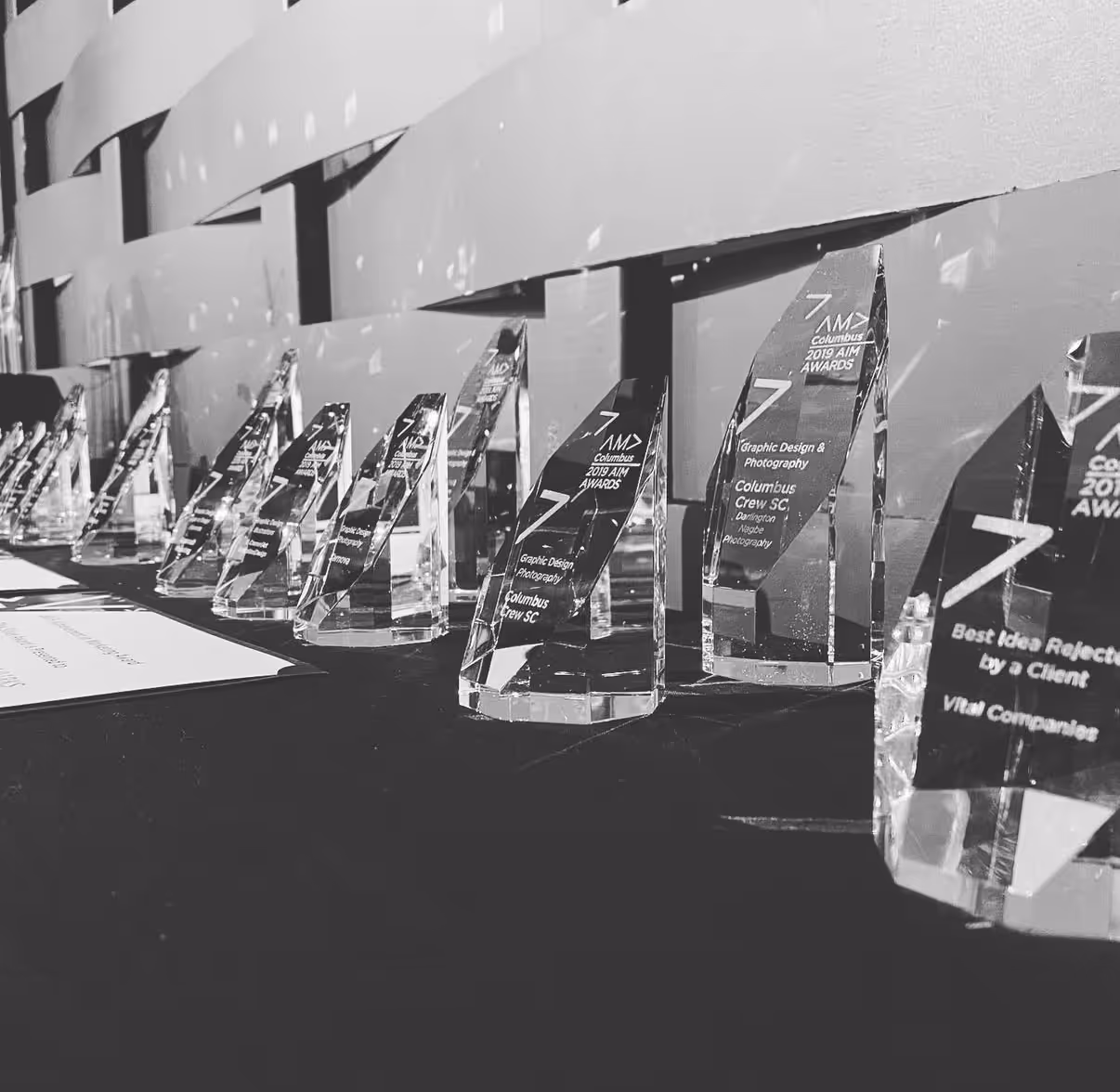 Row of clear crystal awards with engraved text displayed on a black tablecloth.