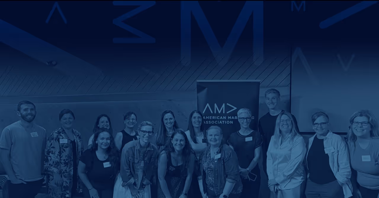 Group of smiling people posing together in front of an American Marketing Association banner.