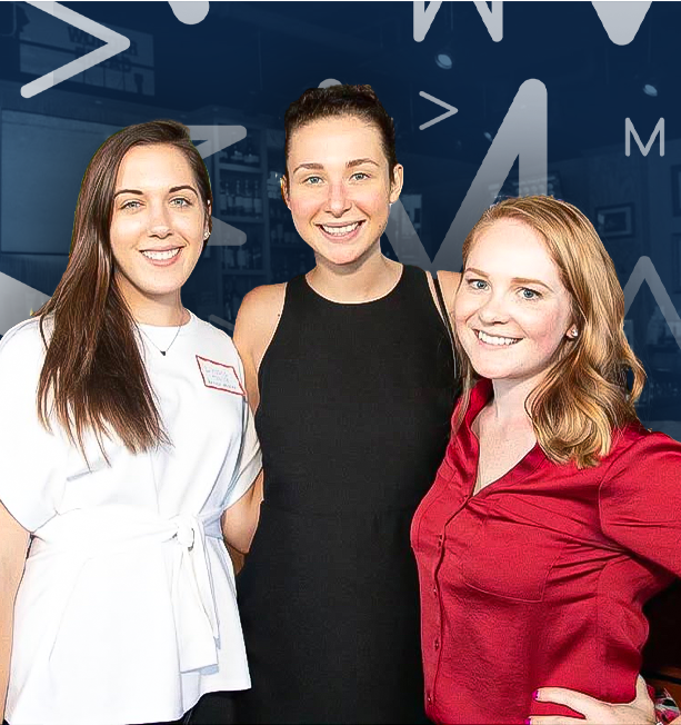 Three smiling women standing closely together indoors, with a dark blue background with white geometric shapes and letters.
