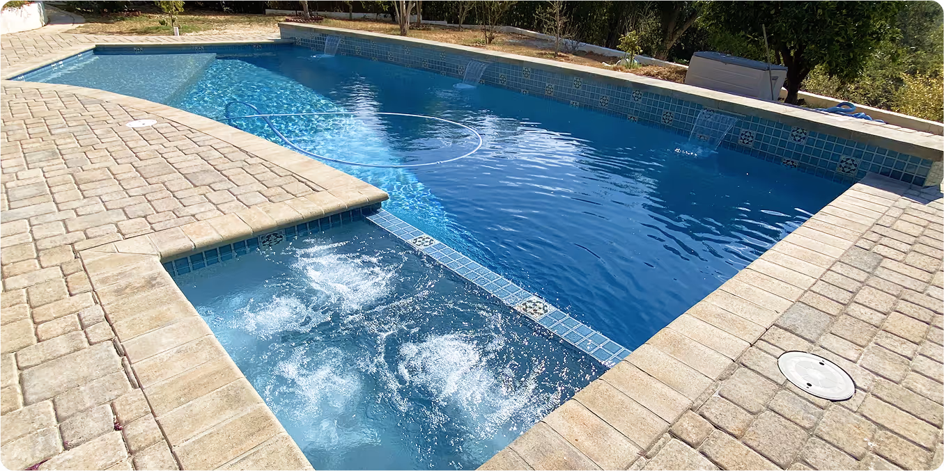 Custom swimming pool with spa and water features, surrounded by stone deck