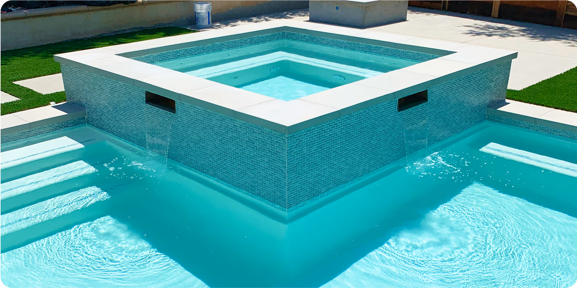 Modern square swimming pool with blue-green tiles and surrounding deck