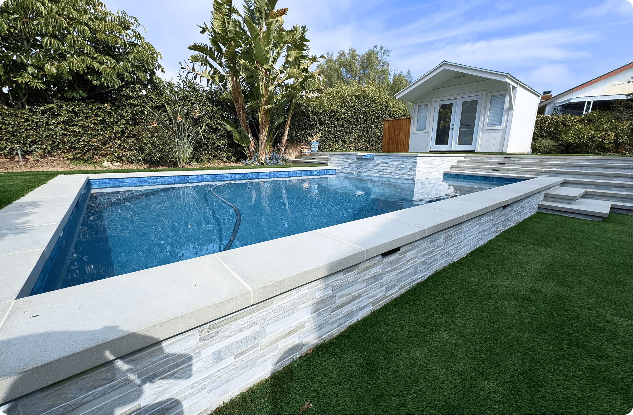 Modern backyard with raised blue swimming pool and white stone landscaping