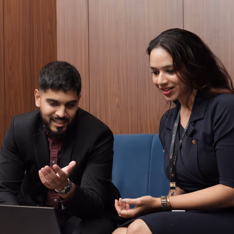 G10X employees, Indian man and woman discussing in front of a laptop