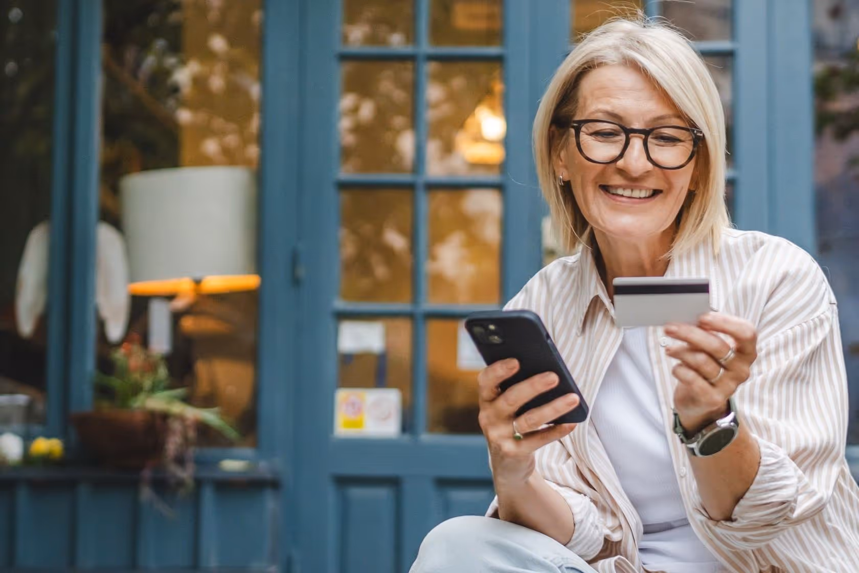 Older woman shopping with credit card in hand shopping on her phone