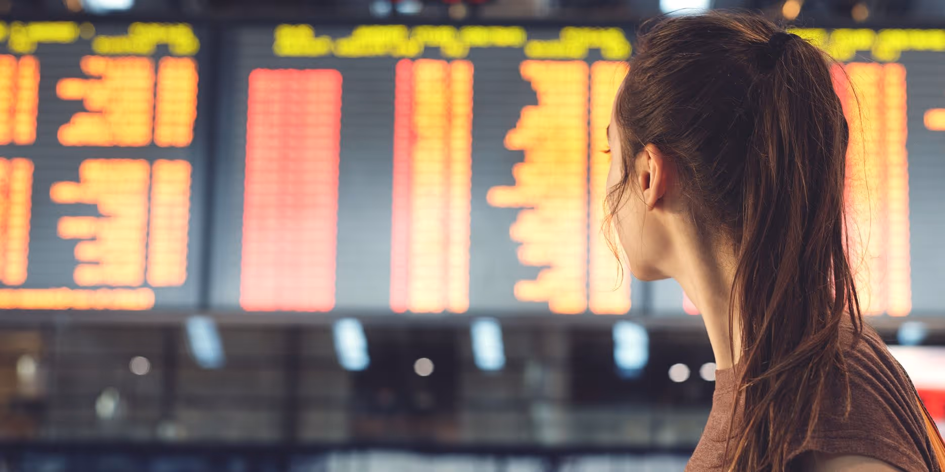 Woman standing in front of an airport schedule board