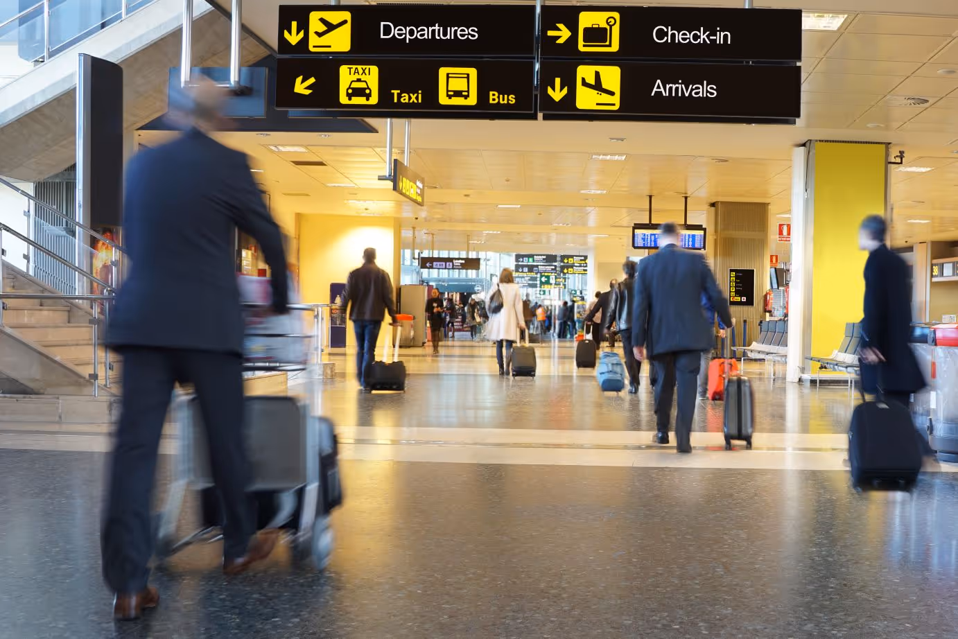 Multiple people walking with luggage at an airport
