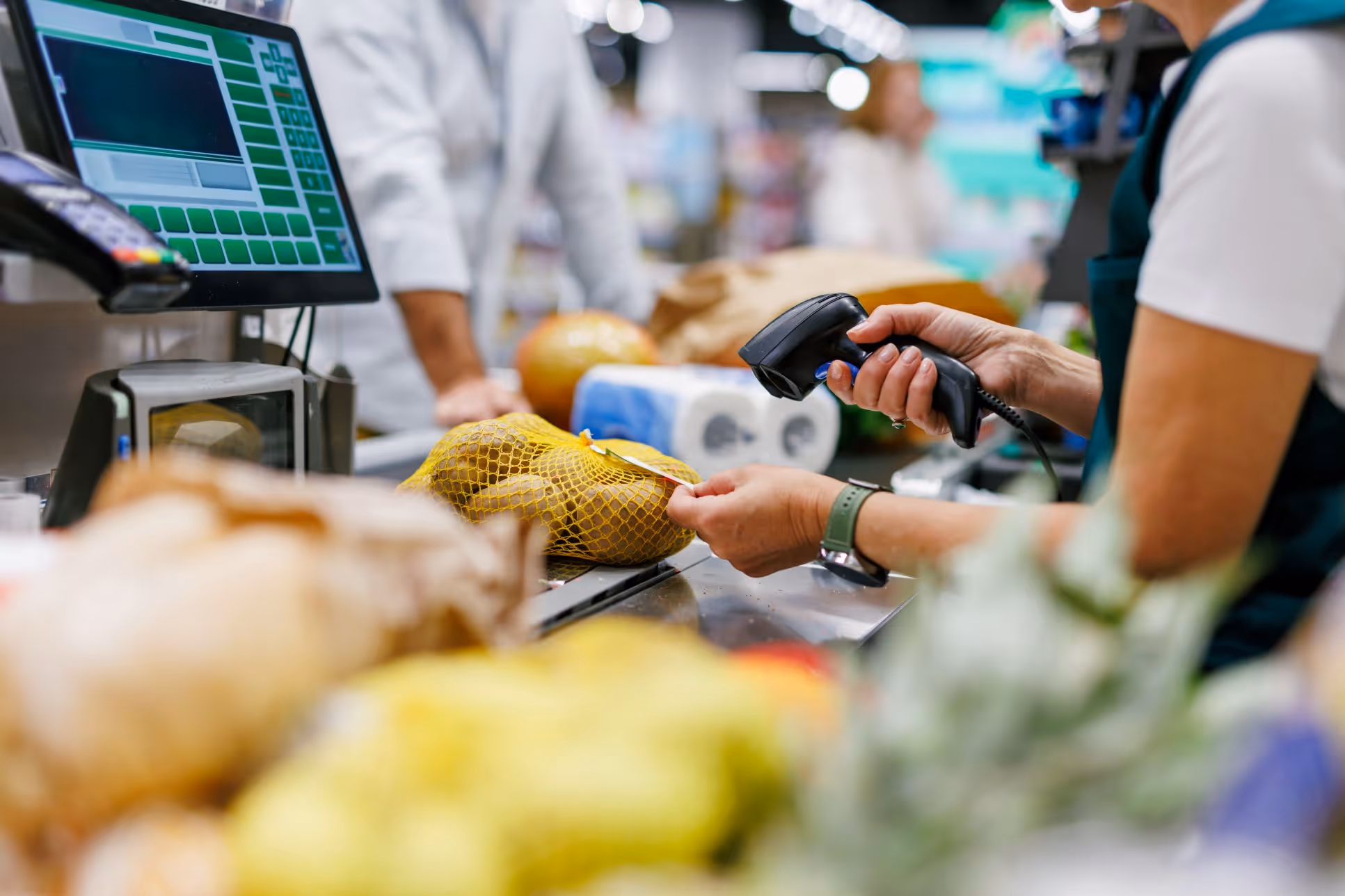 A person at a supermarket checkout counter scanning an item