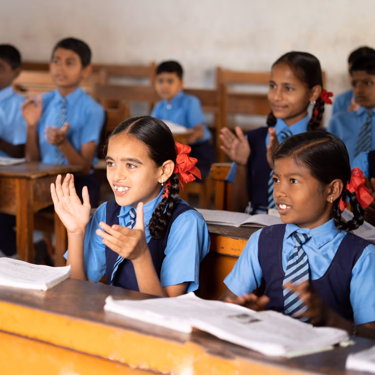 Indian school children sitting in a classroom and clapping