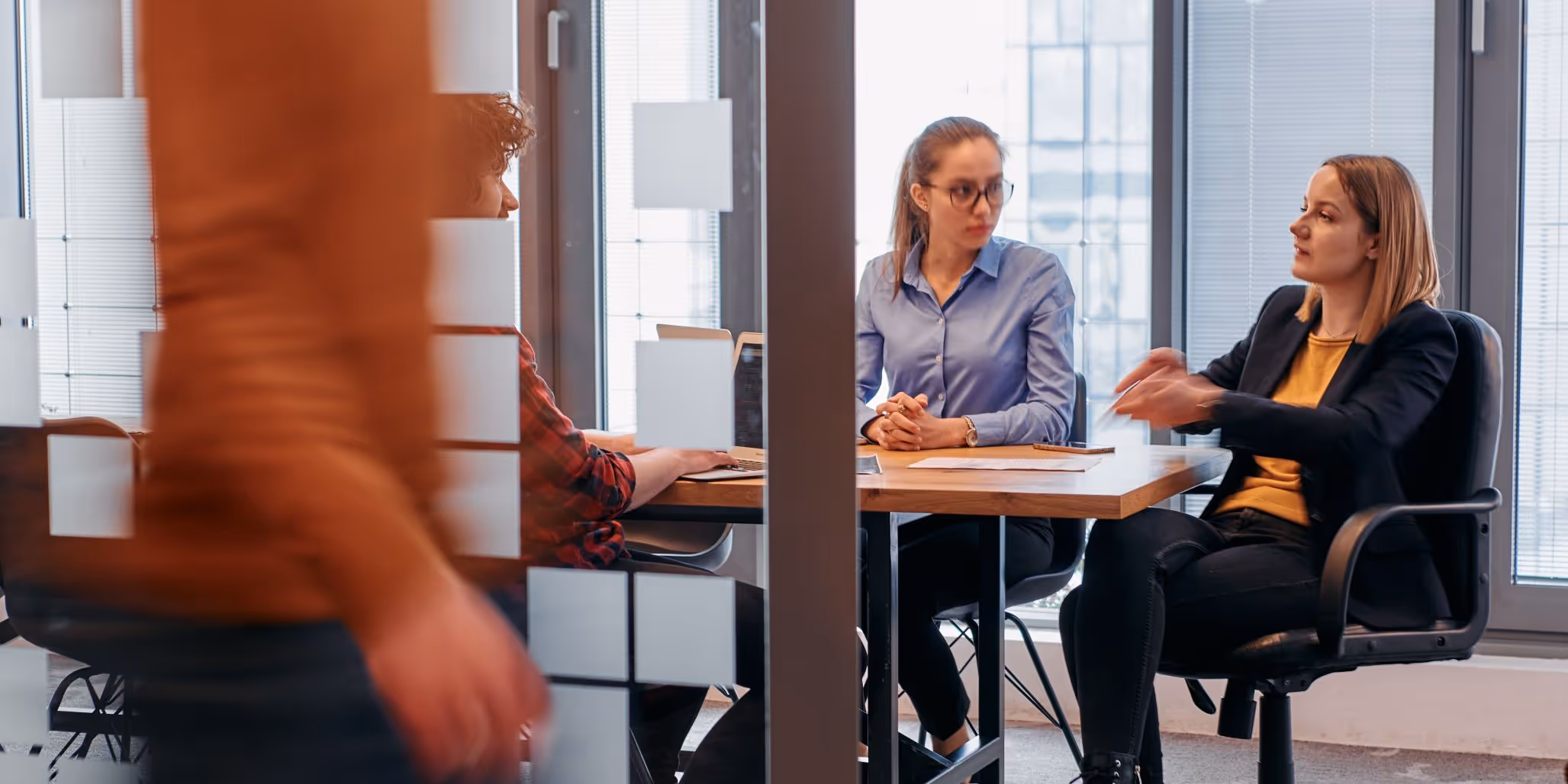 Two women and one man sitting in a meeting room discussing