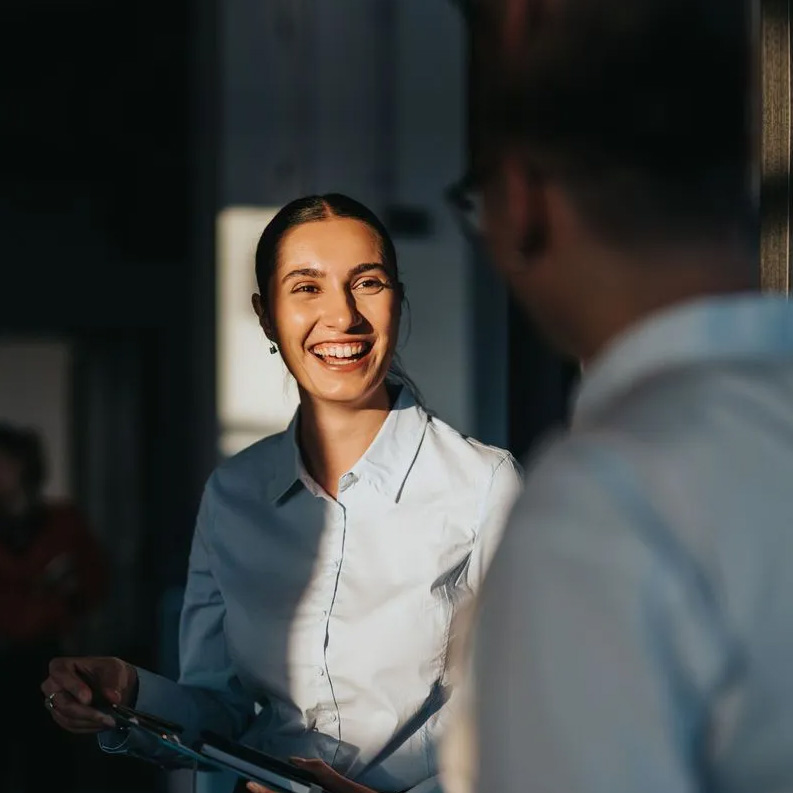 A smiling woman looking at a man in the foreground