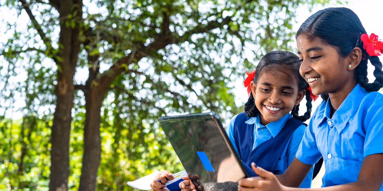 Two India school girl looking at a laptop outside