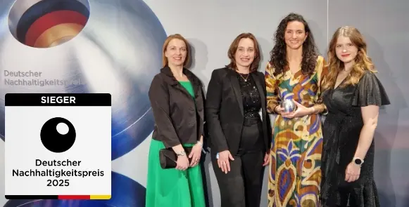 Vier Frauen in Abendkleidung posieren zusammen vor einem Hintergrund mit dem Logo des Deutschen Nachhaltigkeitspreises 2025.