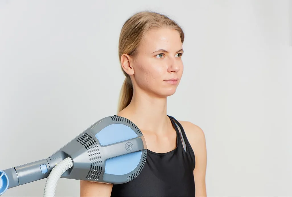 Жінка отримує апаратну фізіотерапію плеча за допомогою великого високотехнологічного пристрою, ілюструючи топову апаратну фізіотерапію та науково обґрунтовані протоколи фізичної реабілітації.