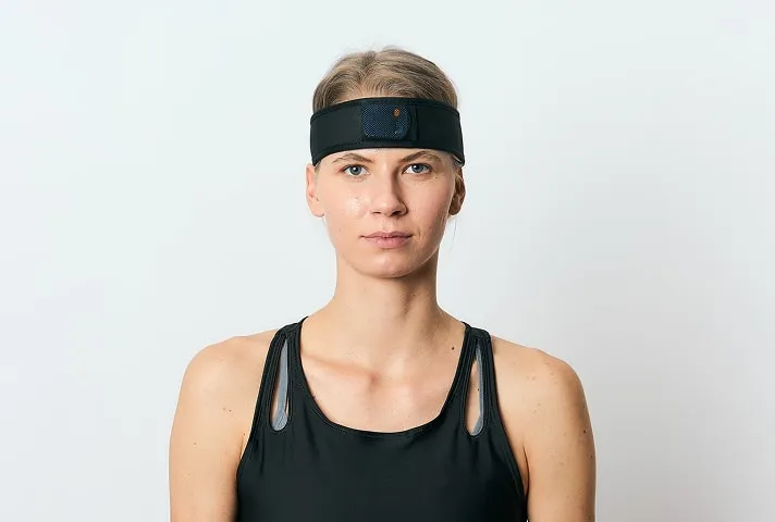 Жінка в діагностичному сенсорі на голові проходить ортодонтичний чекап, мета якого — оцінити вплив прикусу на поставу, баланс та спортивні результати.