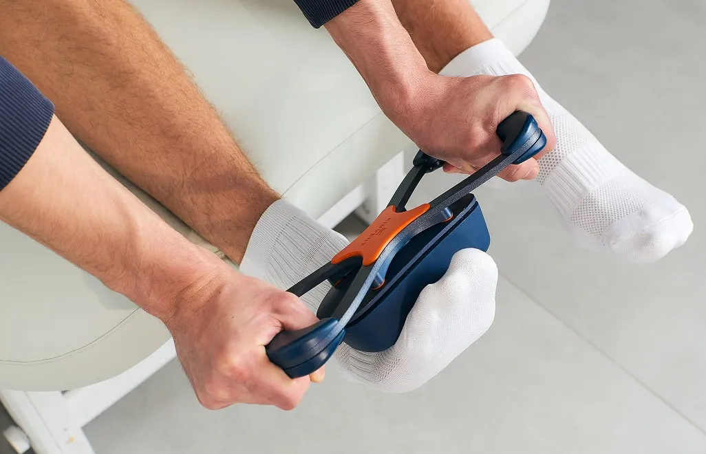 Спеціаліст використовує спеціалізований цифровий прилад для вимірювання біомеханічних параметрів стопи або гомілки клієнта в білому носку.