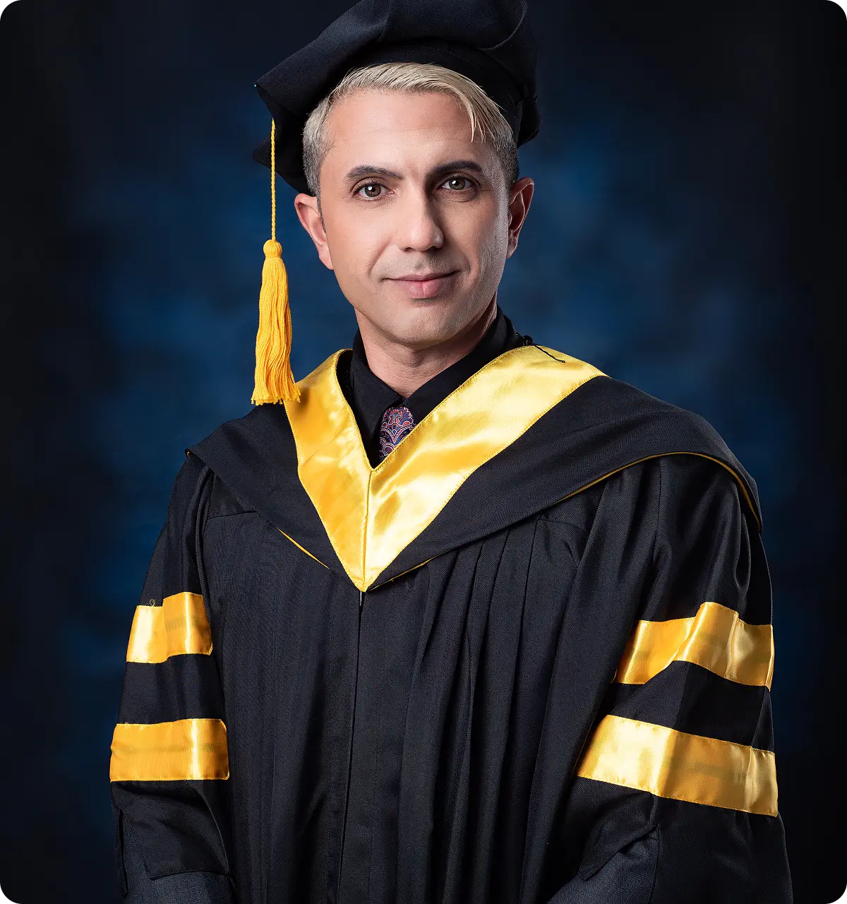 Dr. Sanad Al Murayati wearing a black and gold academic gown and cap against a dark blue background.