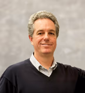 Headshot of the CEO Marcus-Ashby, standing with a grain analysis machine.