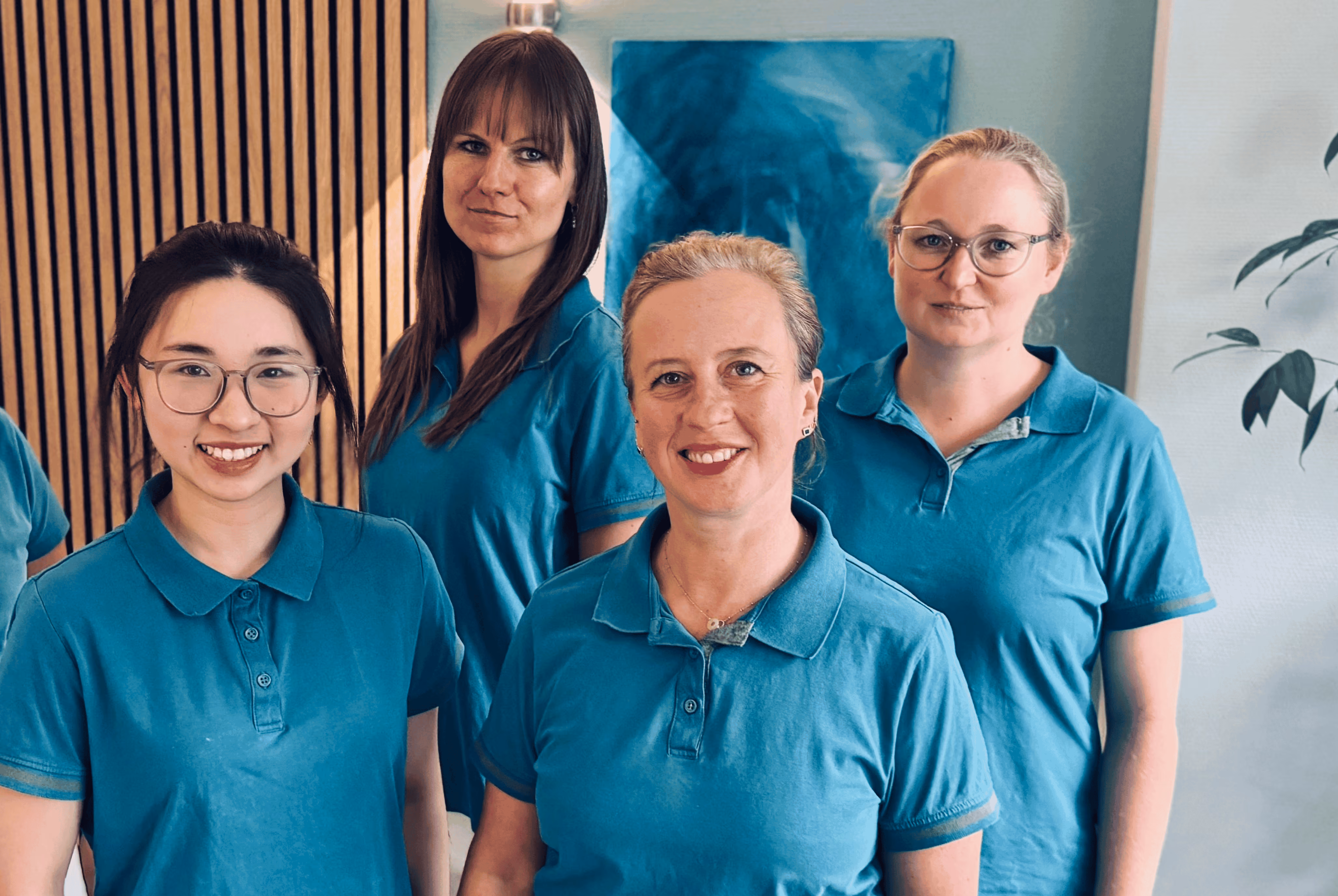 Das Team der Zahnarztpraxis Hamburg Poppenbüttel, vier Mitarbeiterinnen in türkisen Poloshirts