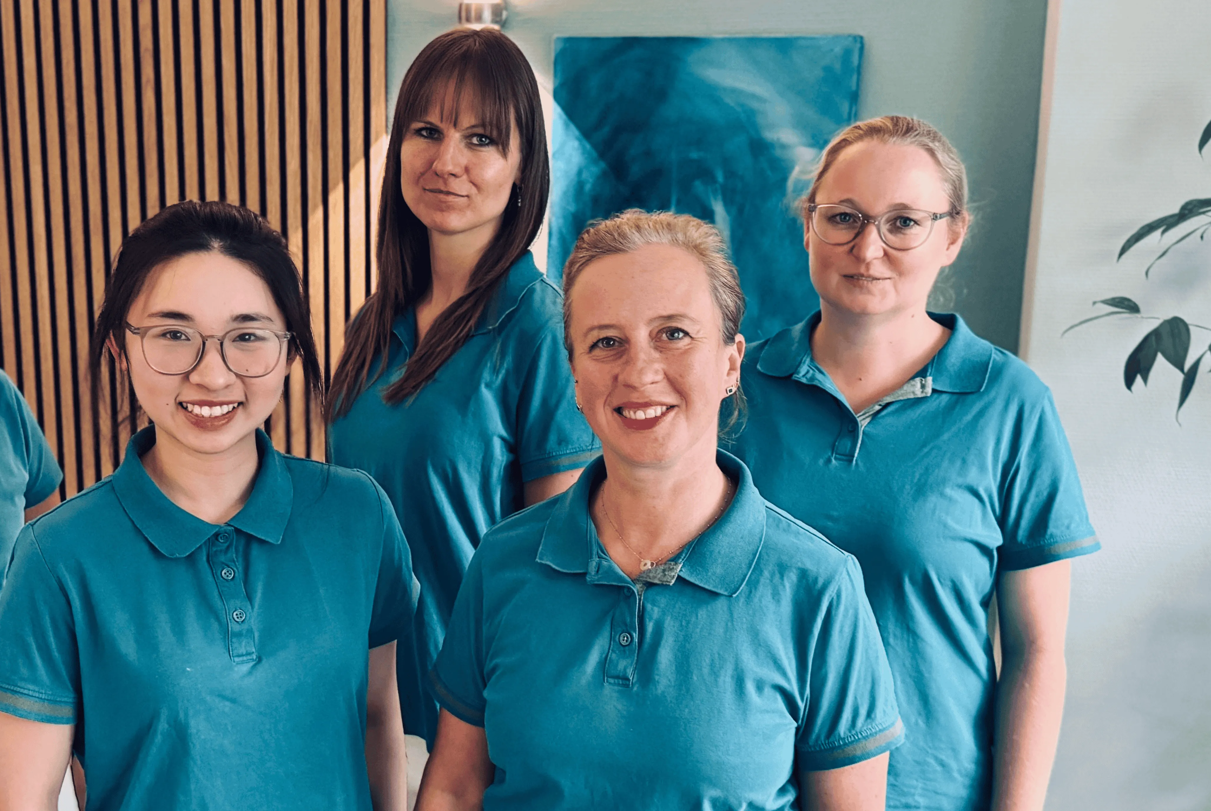 Das Team der Zahnarztpraxis Hamburg Poppenbüttel, vier Mitarbeiterinnen in türkisen Poloshirts
