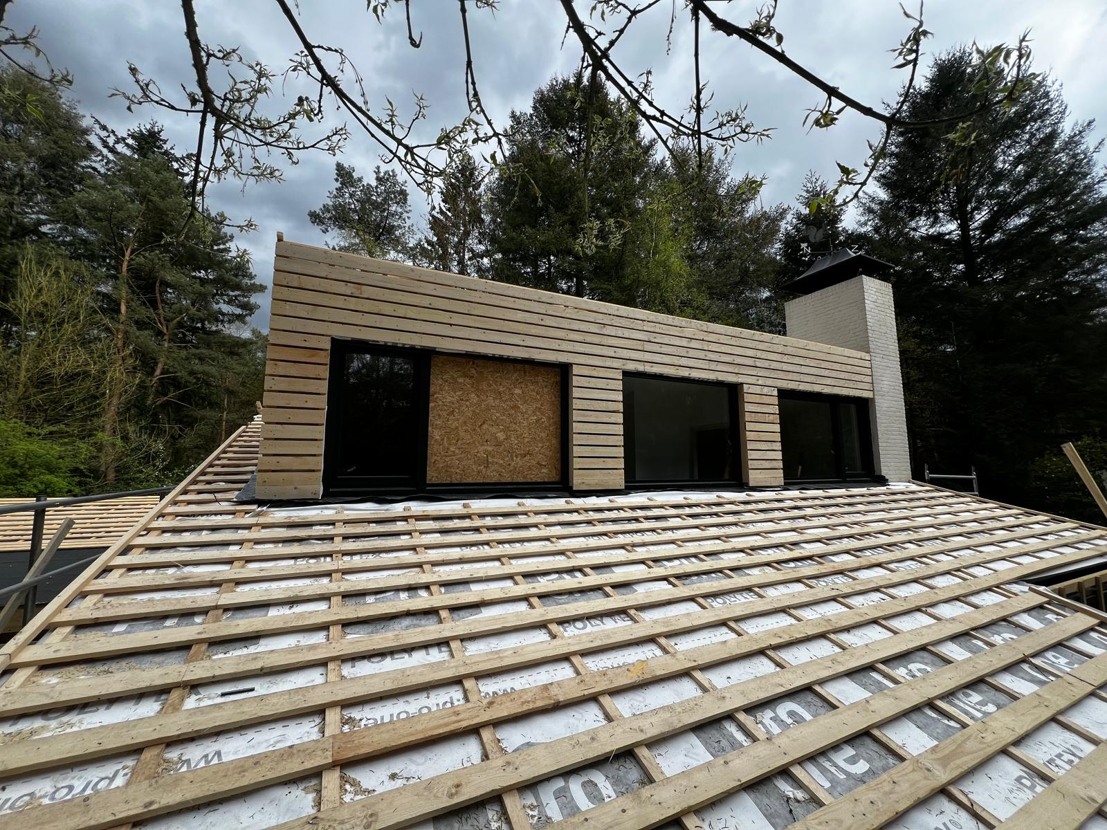 Renovatie van een dak, houten latten, waar het dakwerk op geplaatst zal gaan worden. Ook is er een uitbouw.