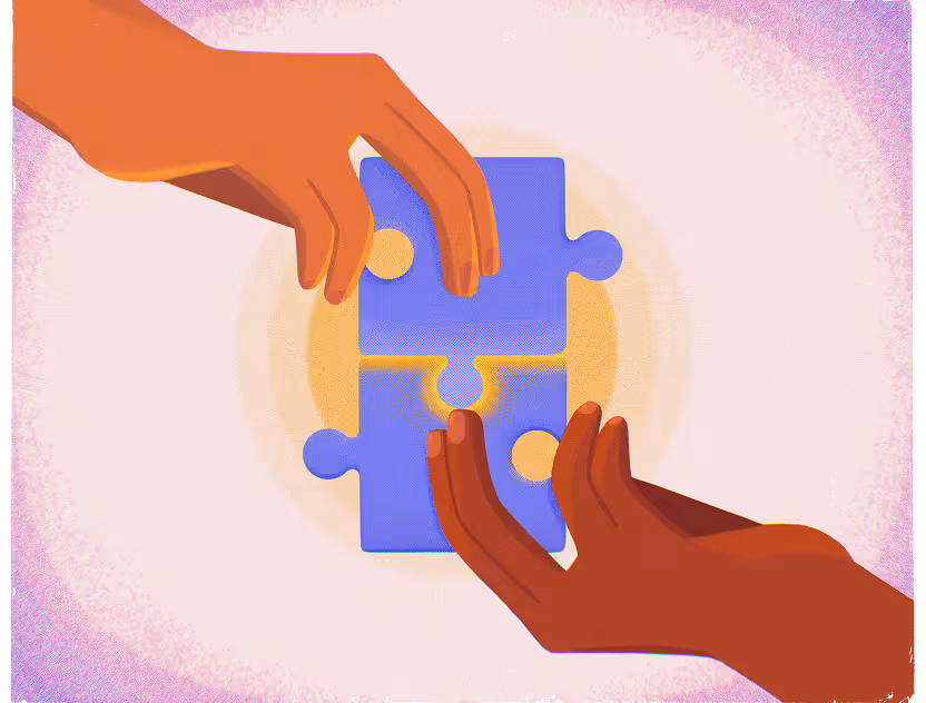 Two hands fitting two blue puzzle pieces together against a soft pink and yellow background.
