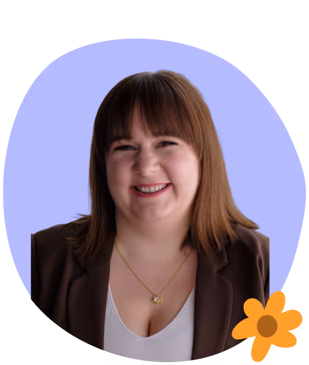 Smiling woman with straight brown hair, wearing a brown blazer and white top, with a gold necklace, on a light purple background with an orange flower graphic.