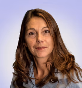 Portrait of a woman with long brown hair wearing a gray collared shirt against a light purple background.