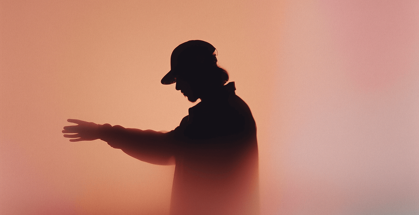 Silhouette of a person wearing a cap and extending one arm against a gradient orange-pink background.