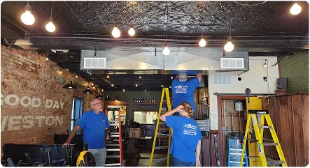 Workers are renovating the interior of a restaurant, with ladders and equipment visible.
