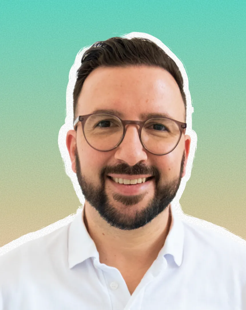 A man with glasses and a beard smiling.