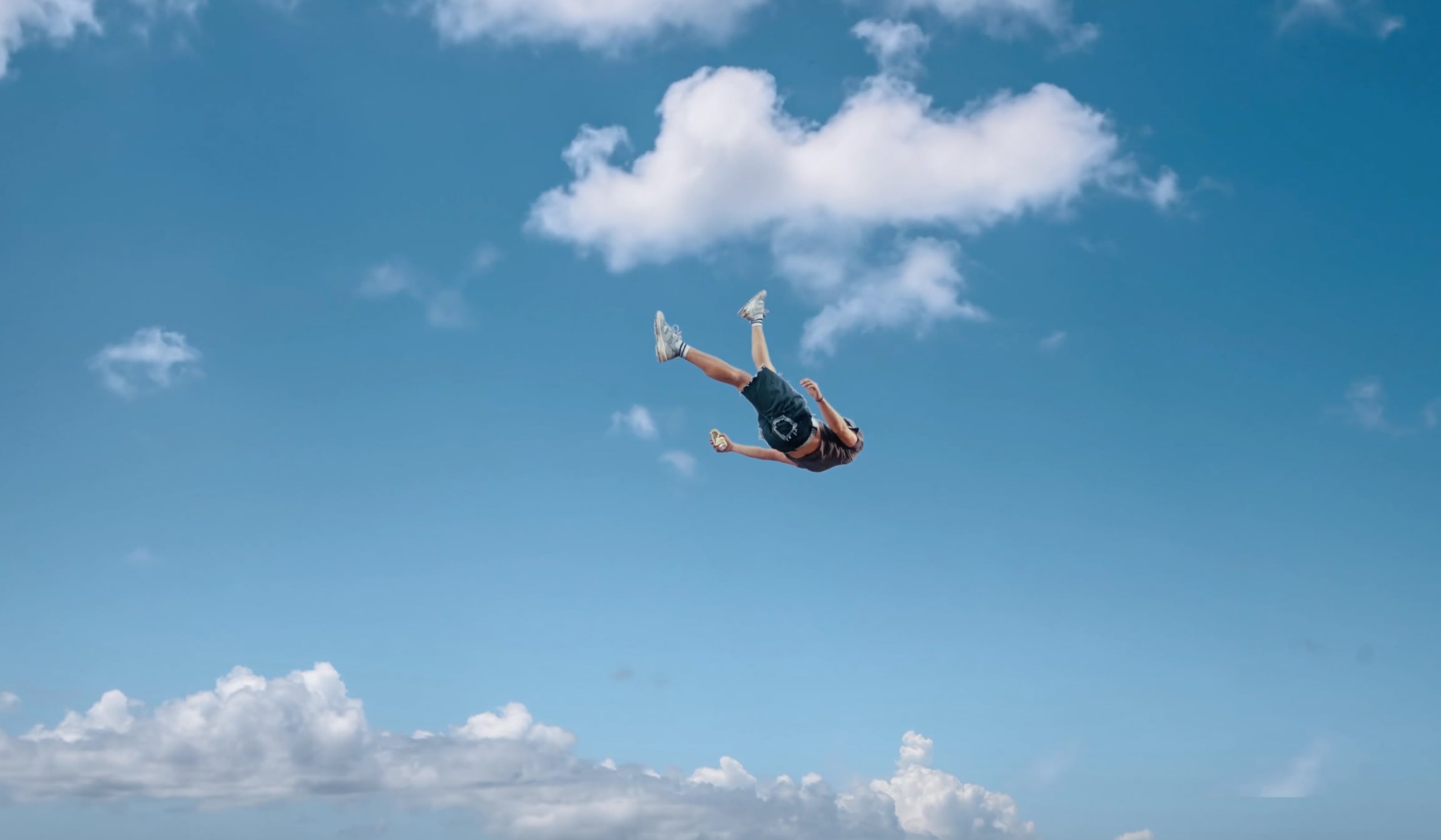 Person mid-air performing a backflip against a blue sky with scattered clouds. - screenshot of the videoclip DISCLOSURE, She's gone, Dance on