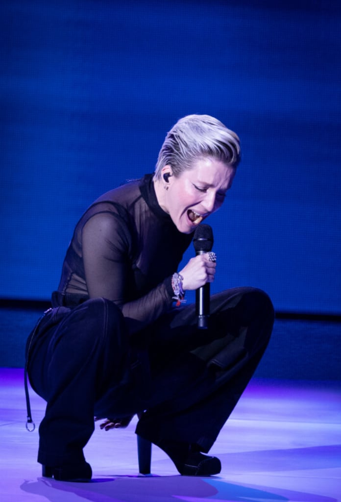 Jeanne Added with short blonde hair crouching and passionately singing into a microphone on a blue-lit stage. - screenshot of the live performance of JEANNE ADDED x La Créole - Mutate during Les Victoires de la Musique