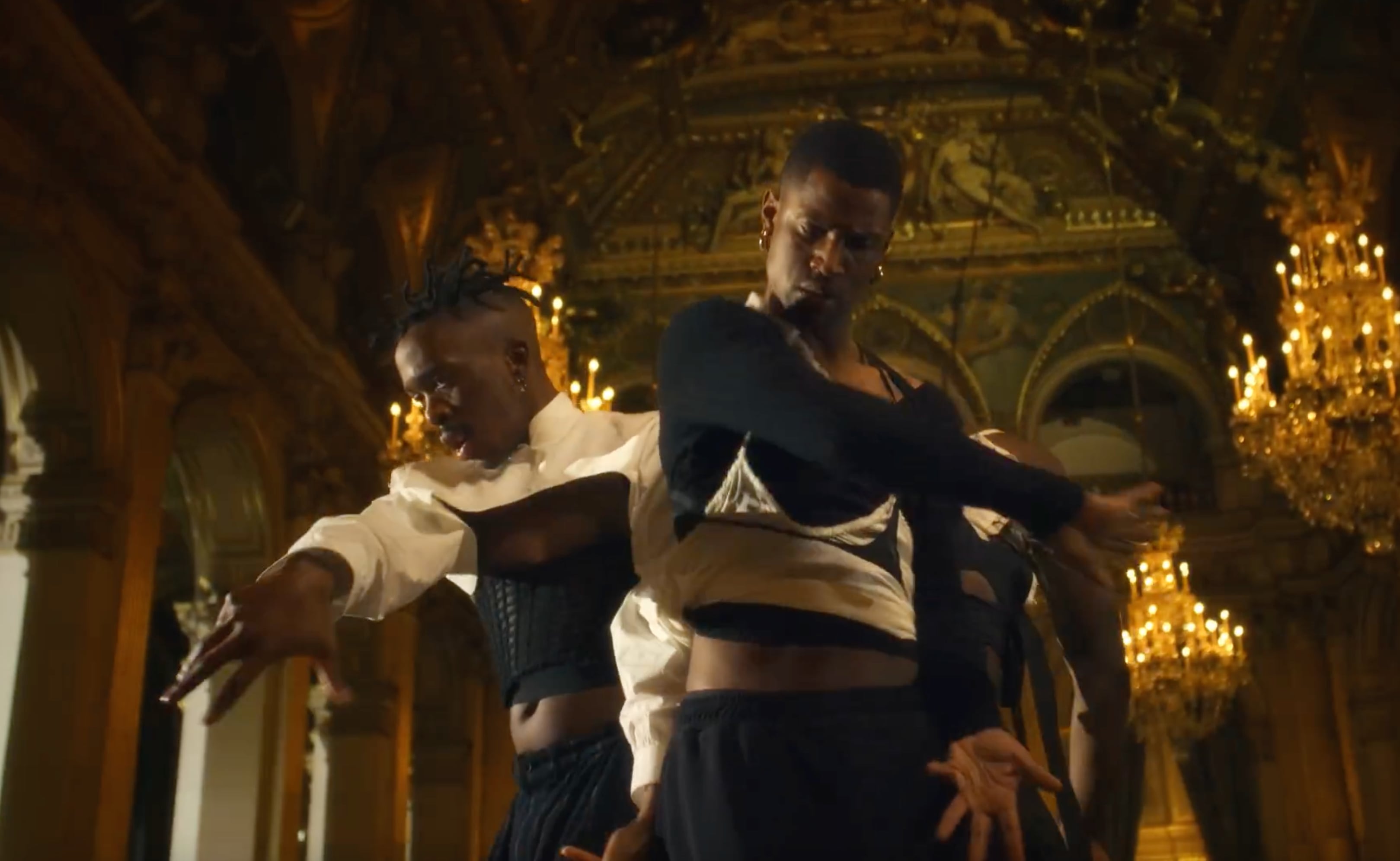 Two dancers in black and white outfits performing in an ornate room with chandeliers. - Screenshot of the video of KOKI NAKANO,
Mue