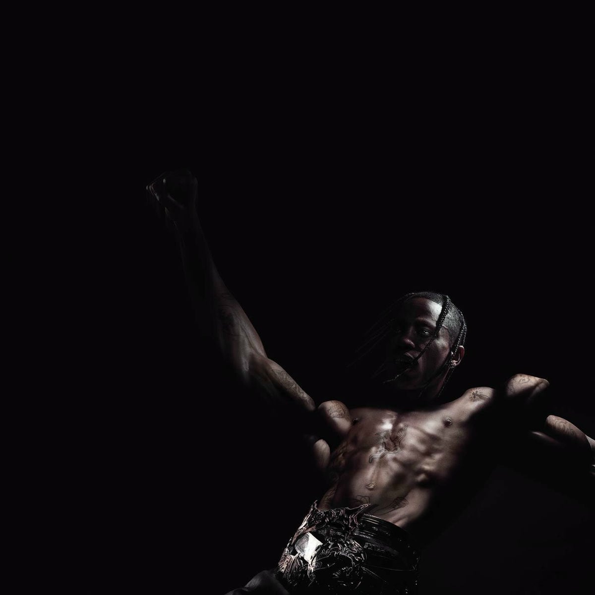 Muscular shirtless man with braided hair raising his fist against a dark background. - Cover of the album - Screenshot of the videoclip TRAVIS SCOTT, Utopia