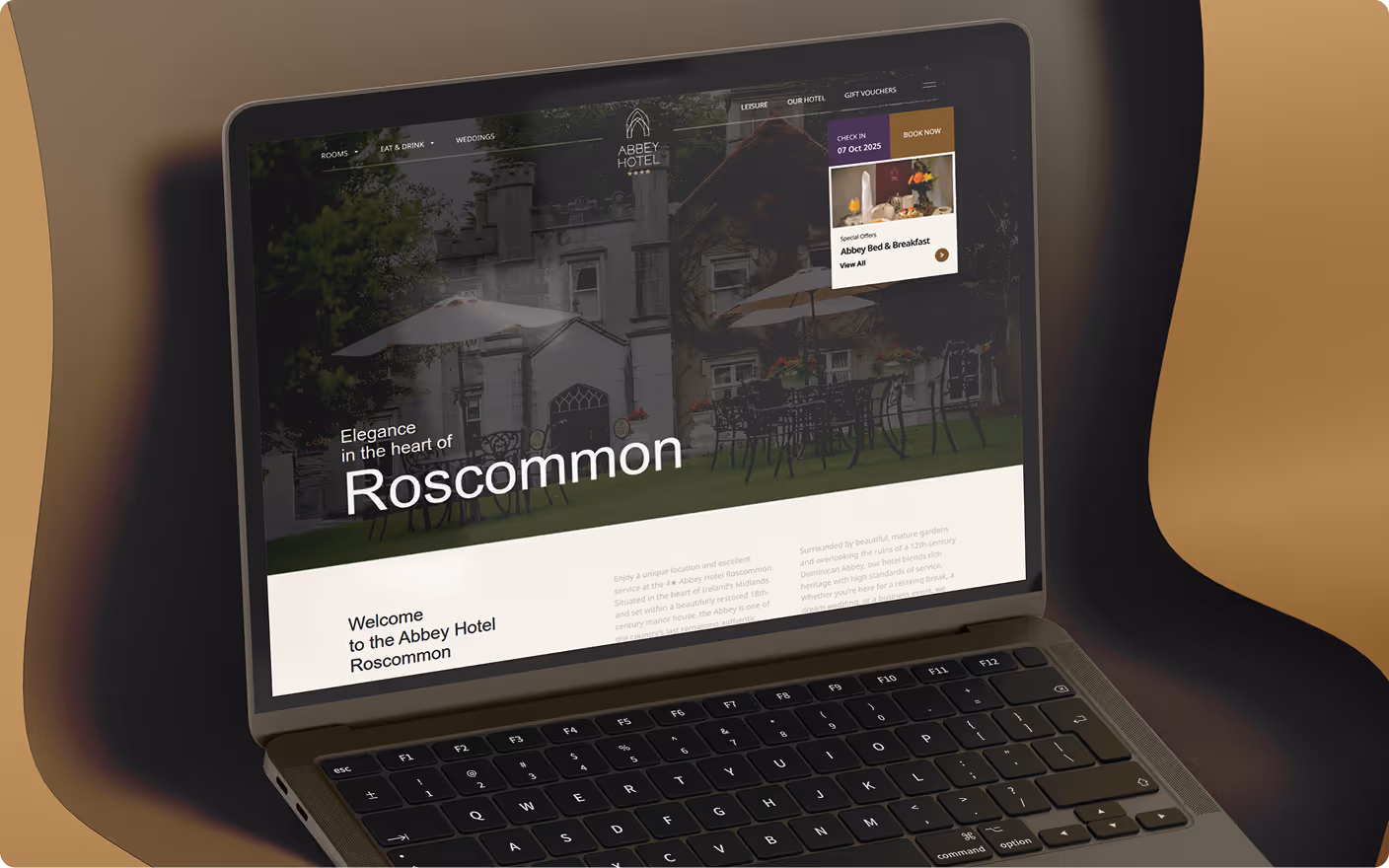 Laptop screen showing Abbey Hotel Roscommon website with outdoor seating and booking options.
