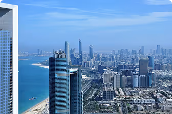 Aerial view of a coastal city with high-rise buildings and blue ocean under a clear sky.