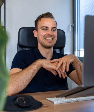 Maximilian Boser sitzt lachend in einem Online-Meeting
