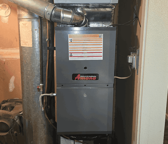 Gray Amana heating and air conditioning furnace unit installed in a utility closet.