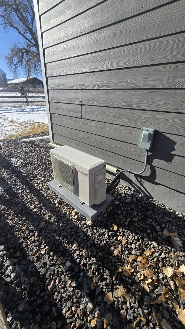 A high-efficiency heat pump unit being installed by a technician in a Colorado backyard - colorado energy rebates for hvac