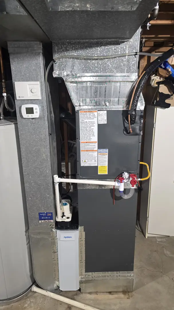 Technician checking thermostat and indoor HVAC components in a home Technician checking thermostat and indoor HVAC components in a home