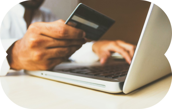 Person holding a credit card and using a laptop for an online transaction.
